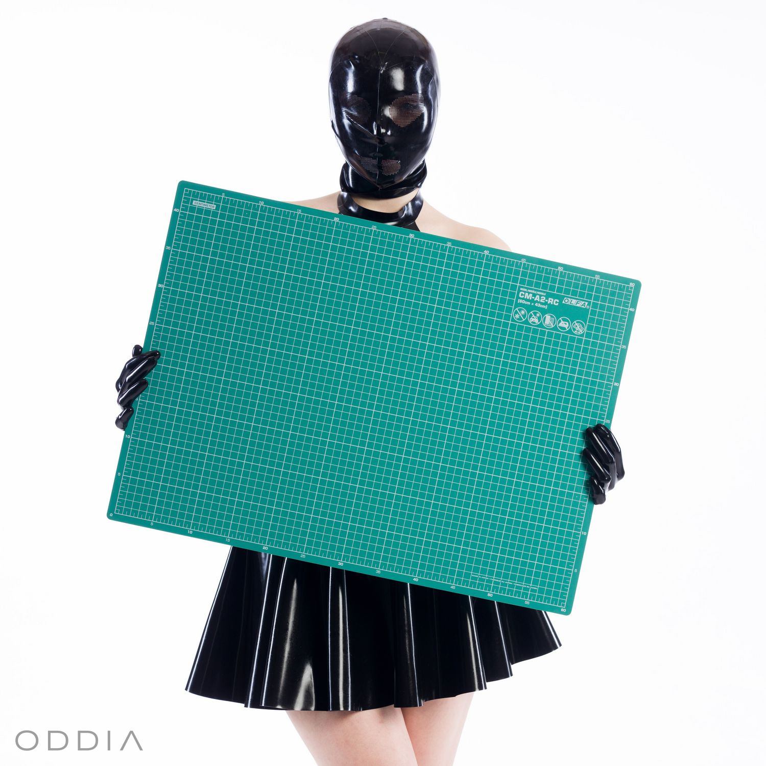 Girl in latex clothing holding a large cutting mat on latex