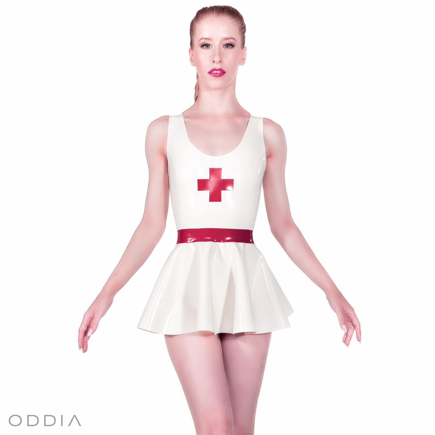 Dívka v bílých latexových šatech s křížem a červeným páskem. Krátká kolová sukně a kulatý výstřih